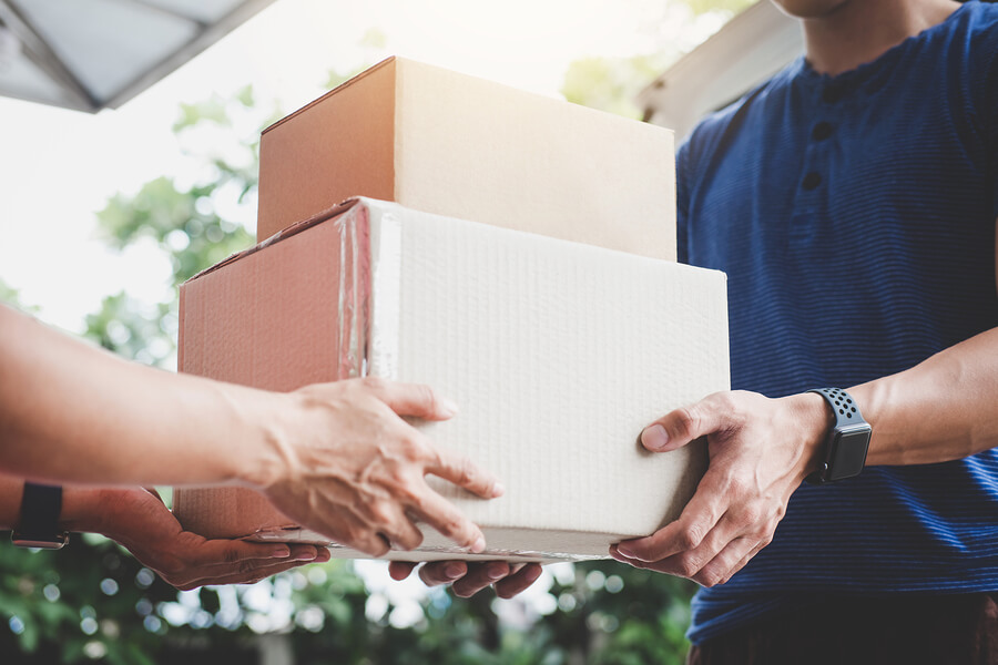 A delivery of two cardboard boxes being made to a man