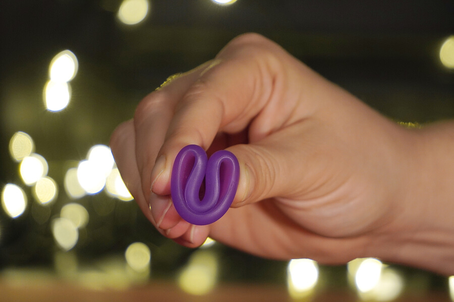 a purple menstrual cup being held in a c-fold
