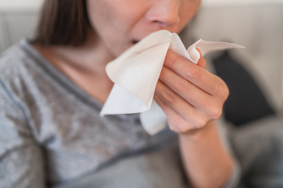 coughing in a tissue with coronavirus symptoms