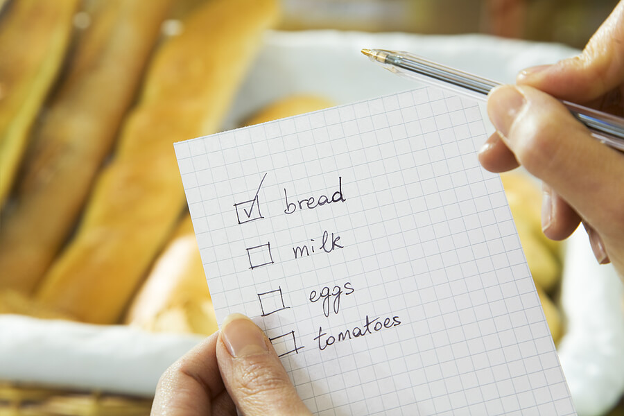 A shopping list with bread, milk, eggs and tomatoes.