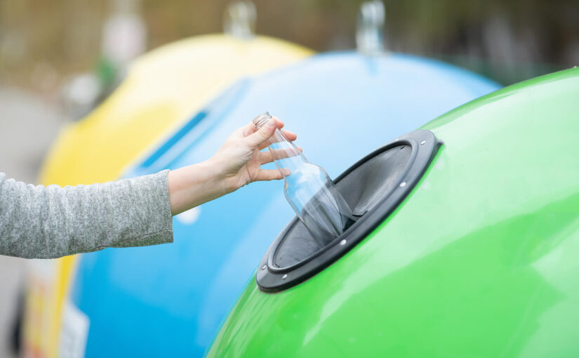 Someone recycling a glass bottle at a bottle bank