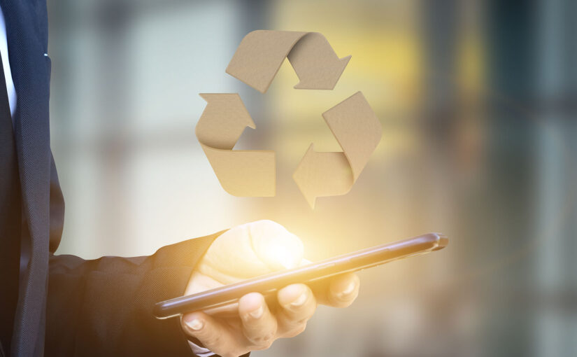 A businessman holding a mobile phone with a large recycling logo above it — recycling concept