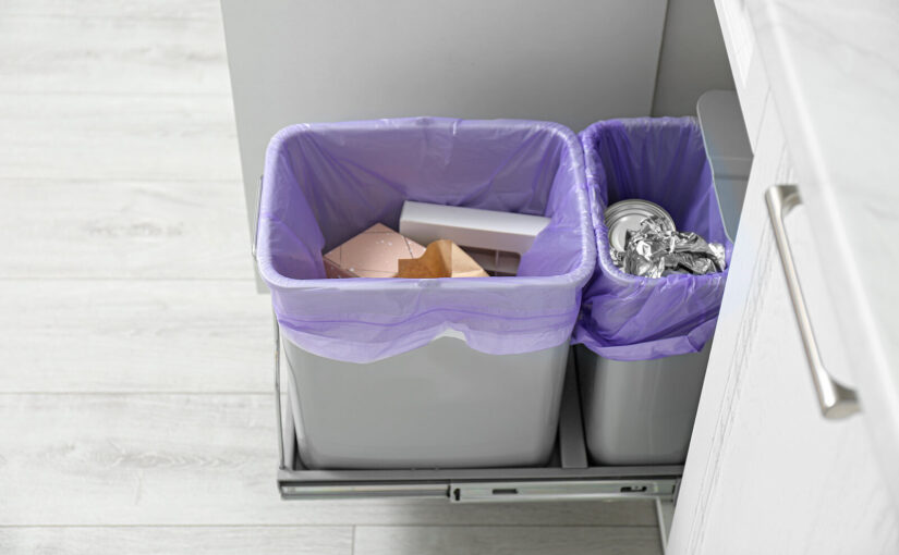 Two grey kitchen bins containing purple bin bags and rubbish