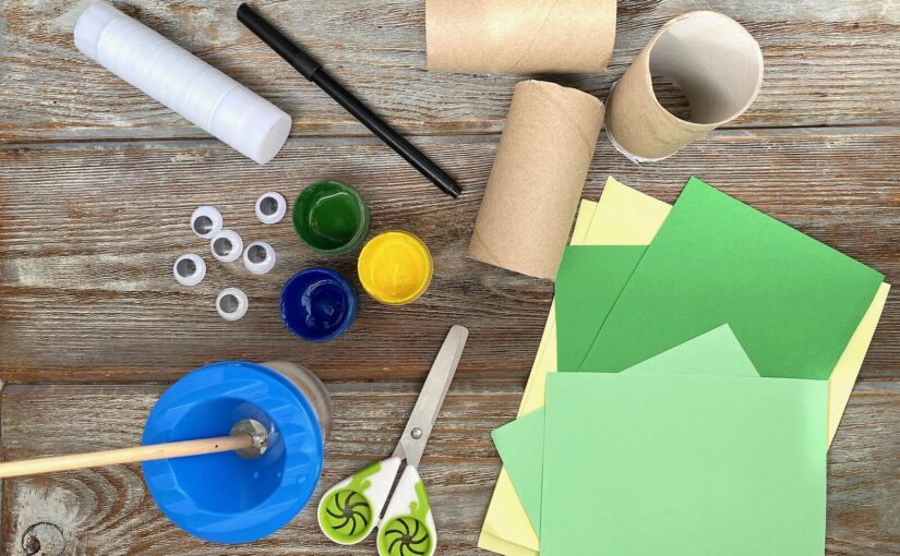 Craft materials for kids' upcycling projects, including toilet roll tubes, paper, scissors, paper glue, and a paint pot.