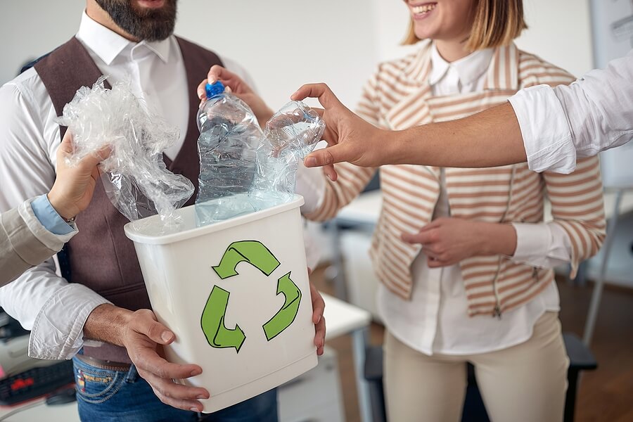 Collecting the trash in the recycling bin at work in a pleasant atmosphere in the office. Employees, job, office