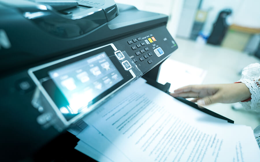 Office worker print paper on multifunction laser printer. Copy, print, scan, and fax machine in office.