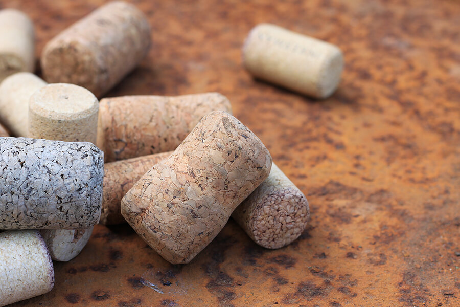 Wine cork from from semi-sweet wine, cork from white wine and cork from red wine among other corks on rusty background