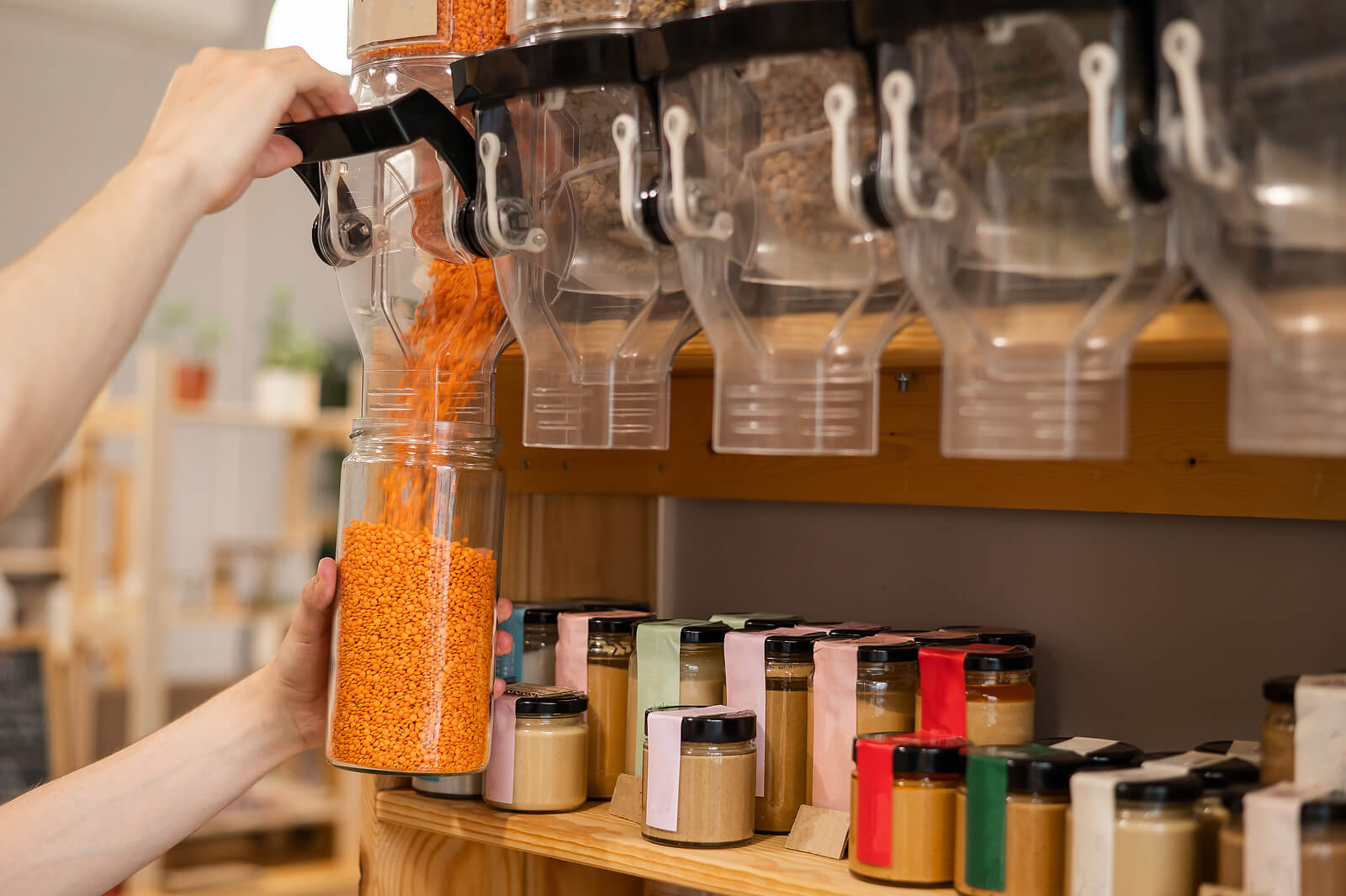 A man using an old jar at a zero waste store to buy red lentils.