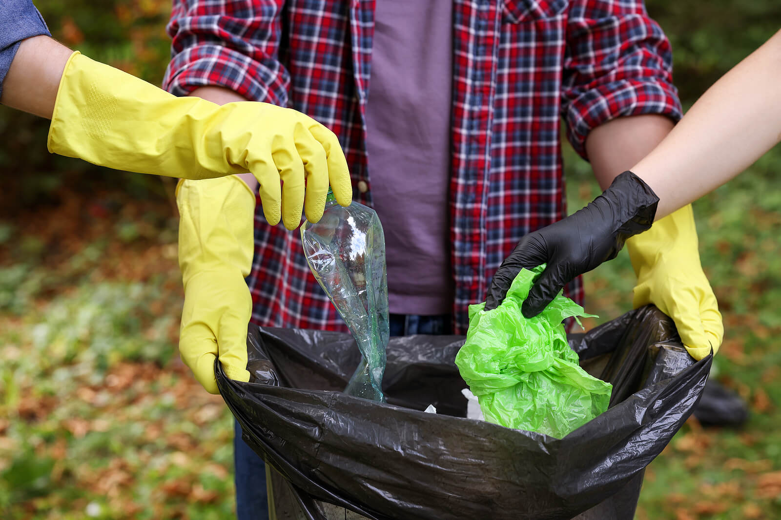 Volunteers placing litter in a black bin bag.